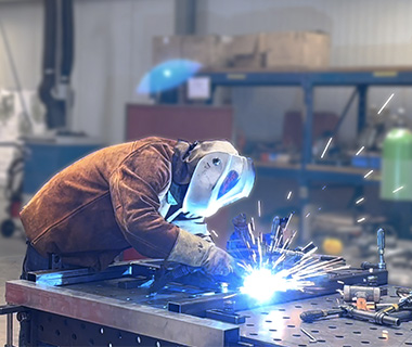 Operai durante la saldatura dell'acciaio nero nel capannone di produzione per progetti di ingegneria meccanica